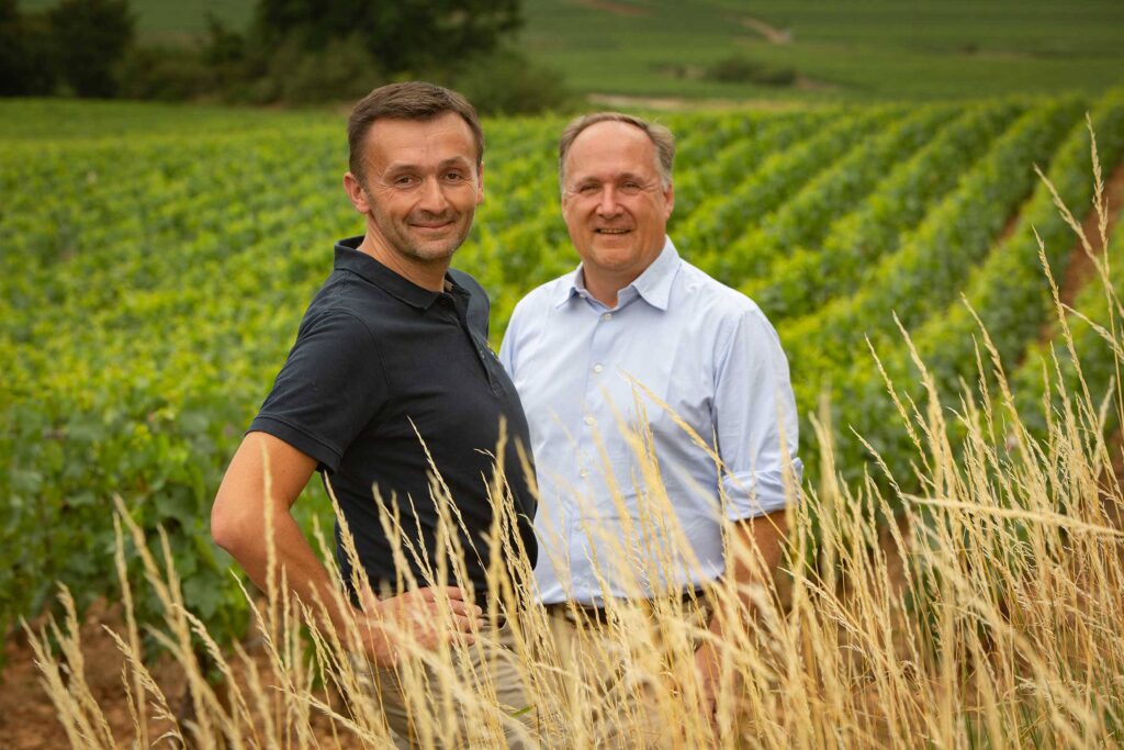 Brice de la Morandiere (great-grandson of the founder Joseph Leflaive) with the winemaker, Pierre Vincent standing near vines