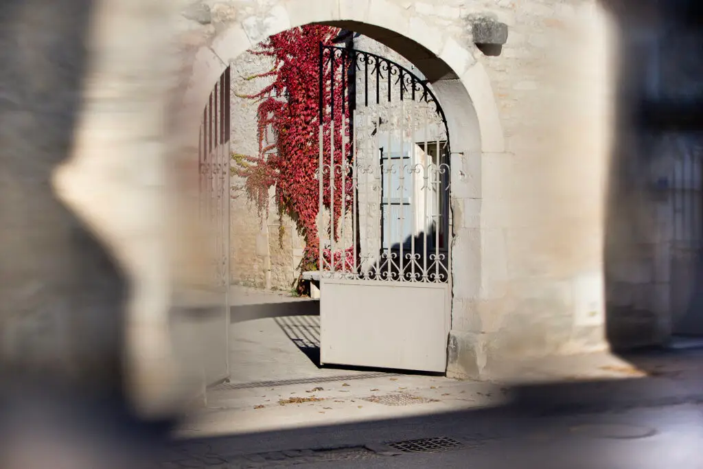 The main gate at Domaine Leflaive with a wall of red ivy on the building behind